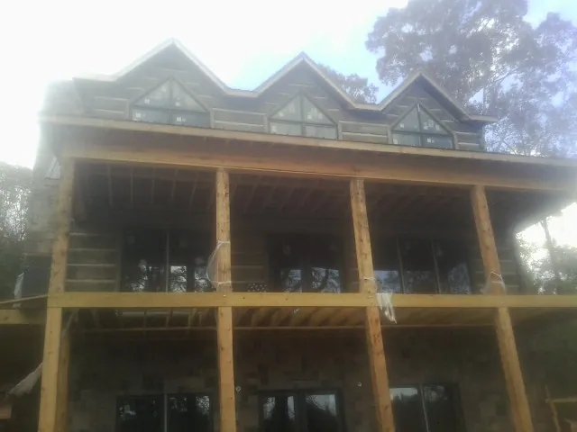 Dormers and porch framing on a large log home under construction — Roof Coating work by our crew in Enterprise